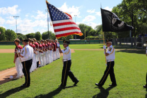 The Apple Valley American Legion Post 1776 Color Guard escorts flags onto the baseball diamond.