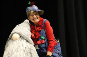 Outgoing President Mary Kuperus stands next to a stuffed gnome.