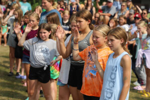 Campers raise their right hands during graduation in August 2023.