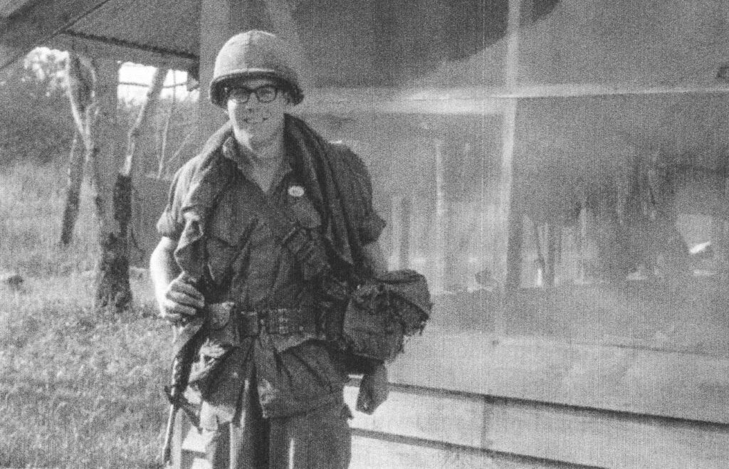 Bill Strusinski, ready with M-16 and aid bag, in his government-issued uniform, helmet and glasses in Vietnam.